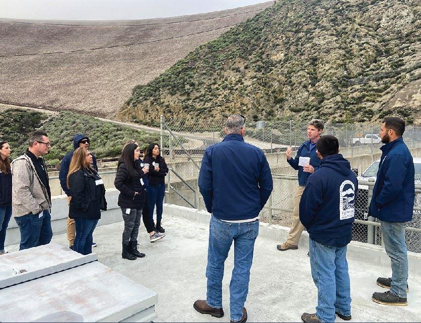 People standing in semi circle under Seven Oaks Dam