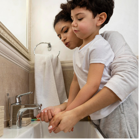 Women and young boy washing their hands in a sink